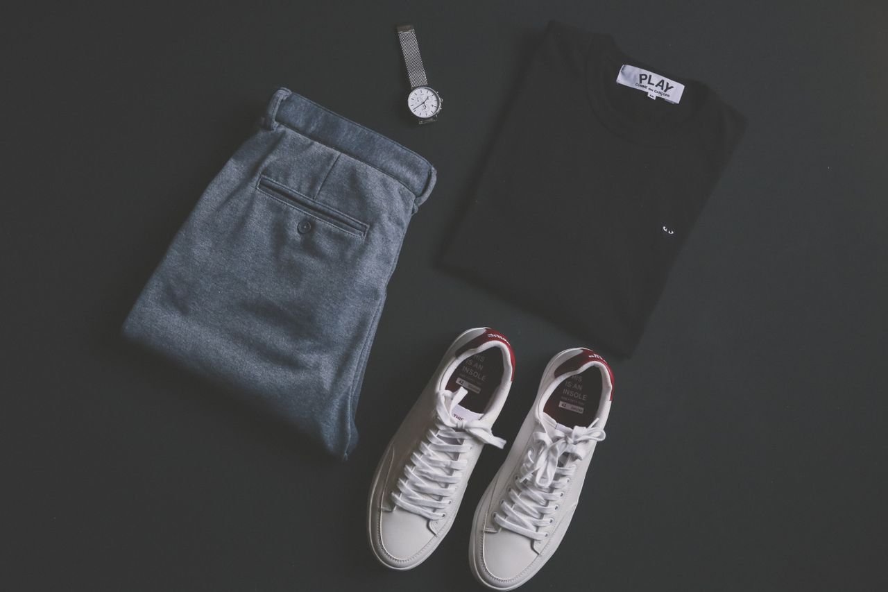 our-journey-01 A stylish flat lay featuring jeans, t-shirt, sneakers, and a wristwatch on a dark background.